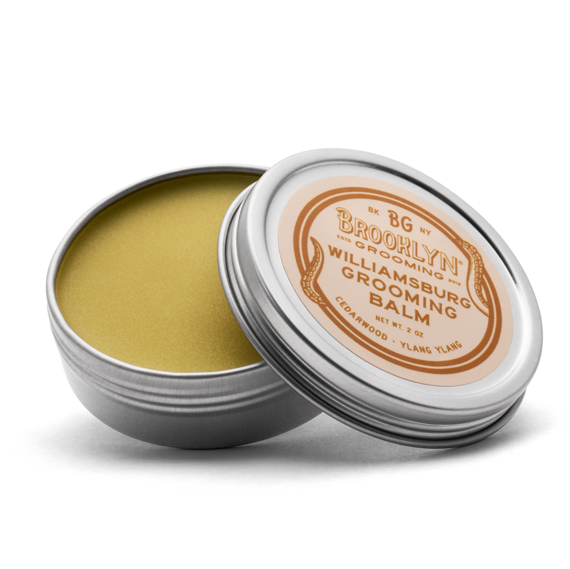 A metal tin with a removable lid containing a yellowish solid grooming balm. The label reads 'Brooklyn Grooming Williamsburg Grooming Balm'.