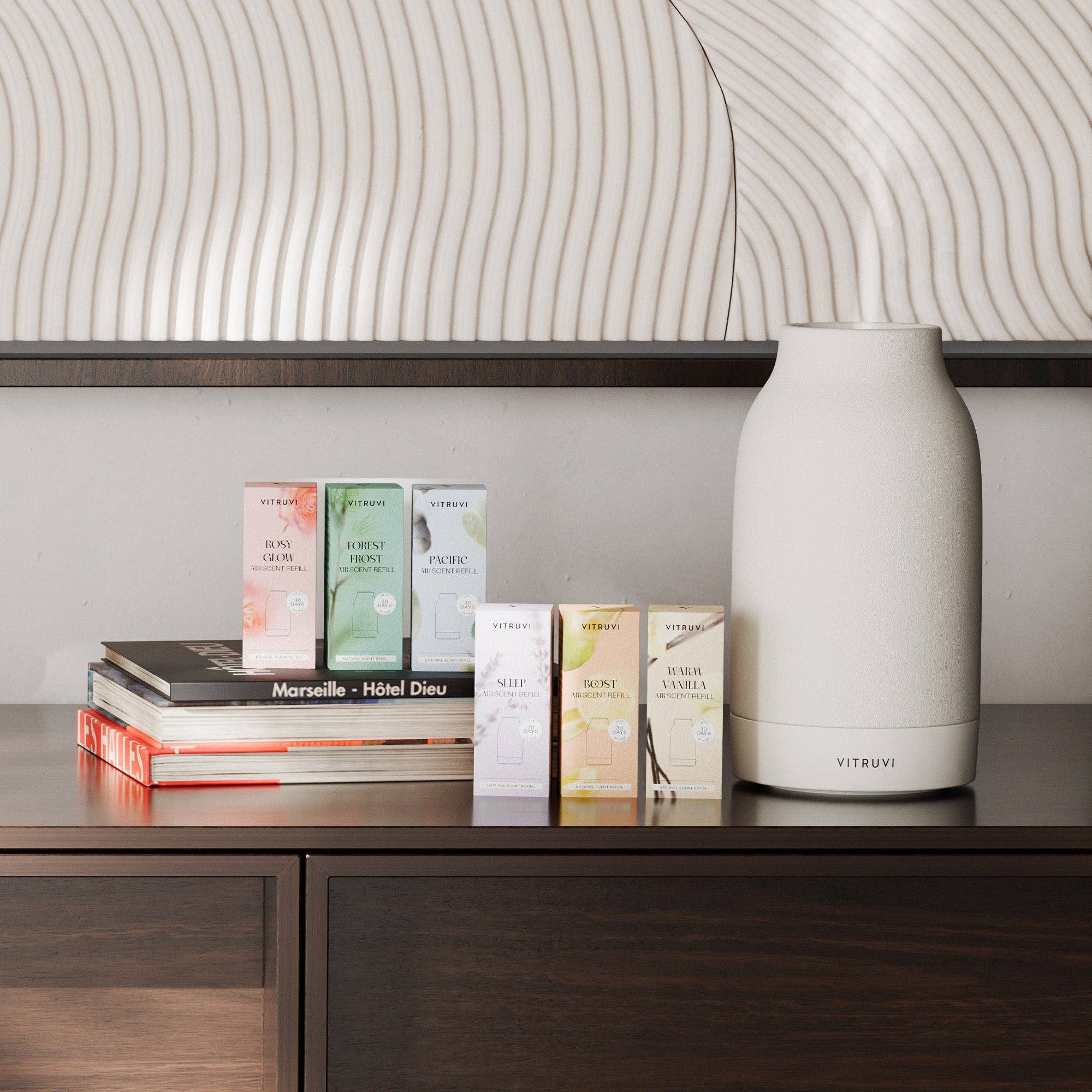 A Vitruvi air diffuser surrounded by fragrance oil boxes