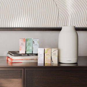 A Vitruvi air diffuser surrounded by fragrance oil boxes
