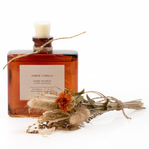 Amber vanilla diffuser bottle with decorative elements on a white background
