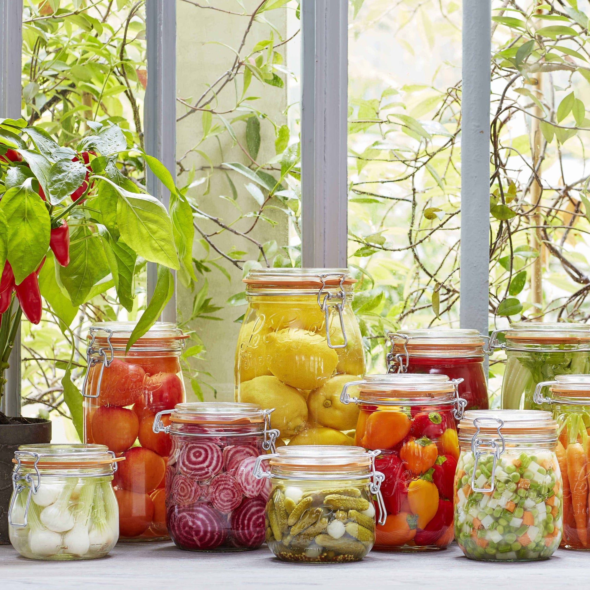 A clear glass Le Parfait rounded storage jar with an orange lid and a stainless steel wire clamp.