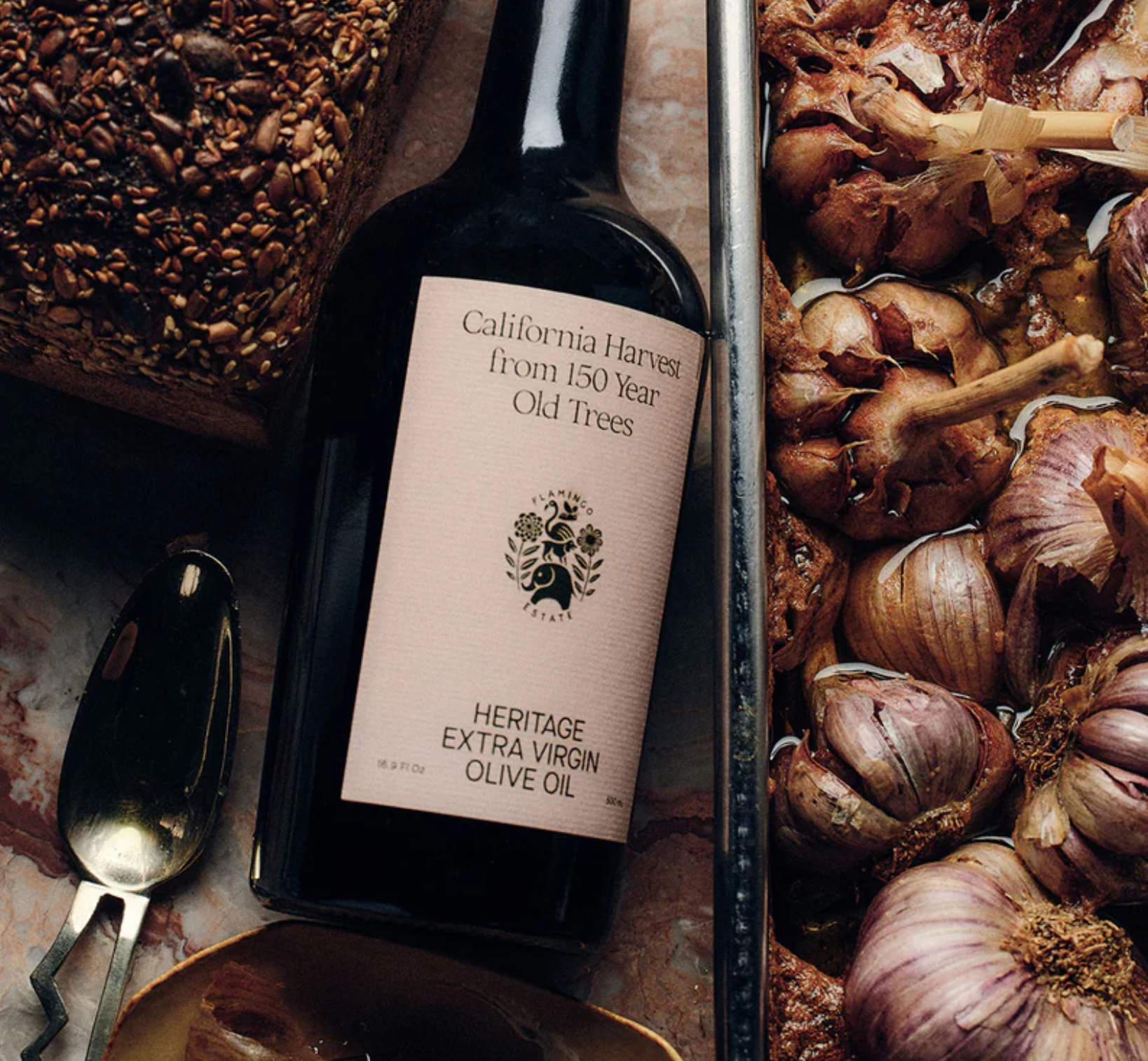 A bottle of Flamingo Estate Heritage Extra Virgin Olive Oil, with a label showing the brand and product name, on a white background with a 'California Harvest' text overlay and a 'Vogue' magazine logo in the top right corner.