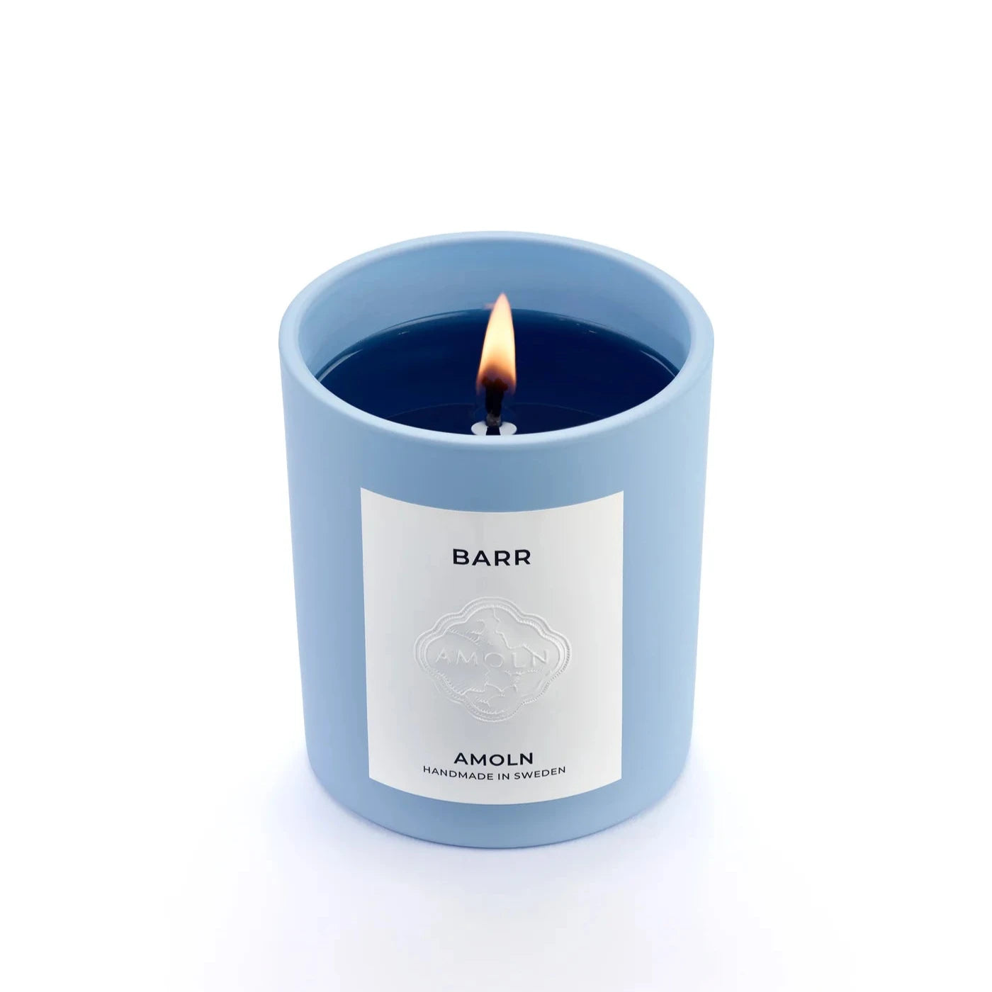 A blue candle vessel with blue wax, with a white label that says Barr.