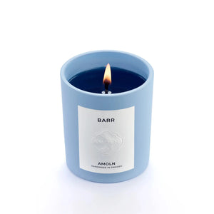 A blue candle vessel with blue wax, with a white label that says Barr.