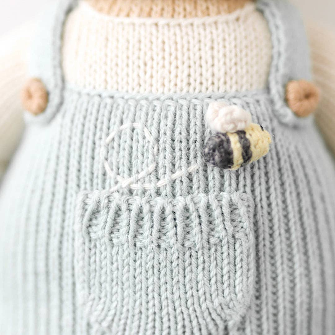 Two hand-knit dolls resembling honey bears, one larger and one smaller, in striped overalls. They are beige, white, and blue in color.