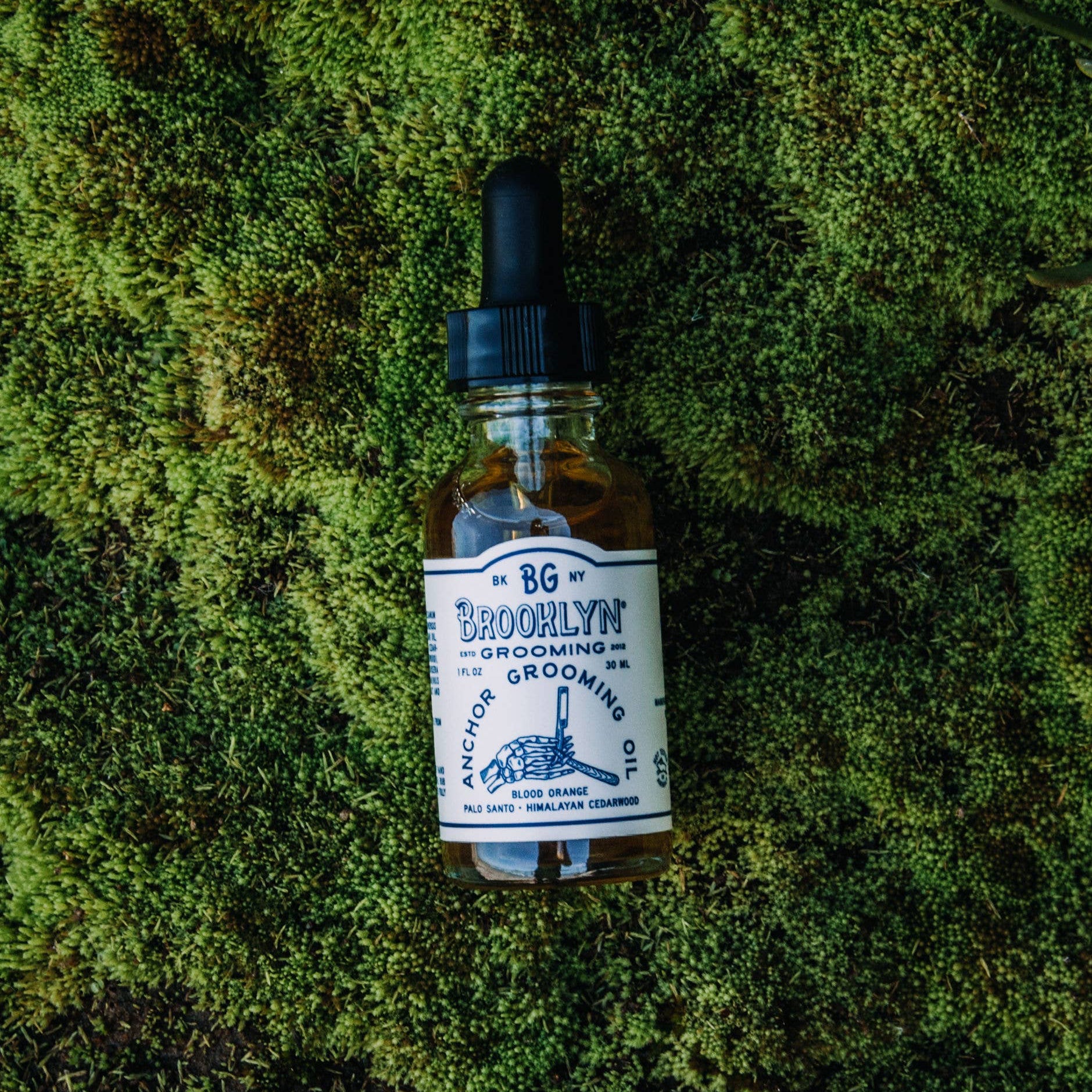 A bottle of Brooklyn Grooming Anchor Grooming Oil with a dropper cap.