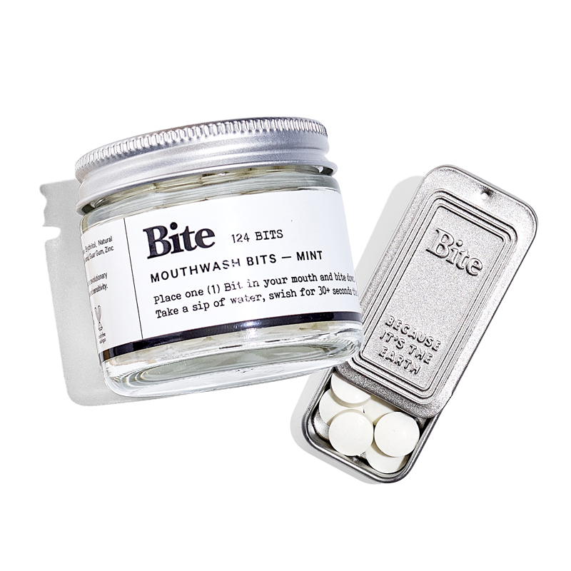 An open aluminum travel tin with toothpaste bits visible inside.