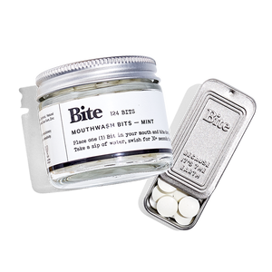 A round glass container of Bite Mouthwash bits alongside a travel tin. 