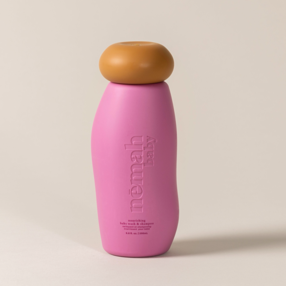 A pink squeeze bottle labeled 'némah' with a brown cap, designed for kids' nourishing wash and shampoo.