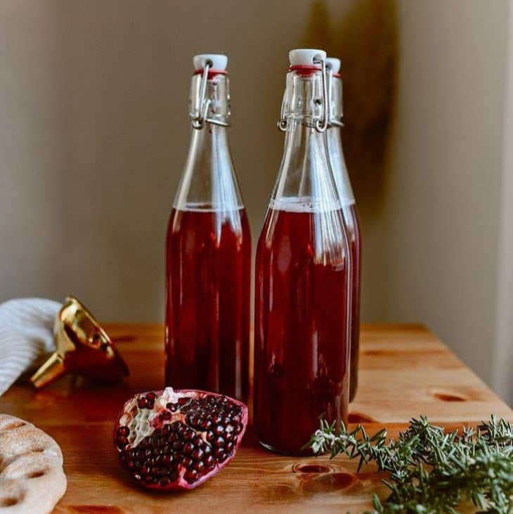 A clear glass swing top bottle with an airtight hinged stopper, suitable for fermenting and storing various beverages.