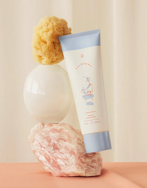 Tube of clean bean soap with a sponge and loofah on a neutral background