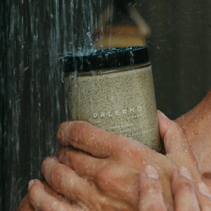 Person using a jar labeled 'Palermo' under running water, likely for a shower or bath.
