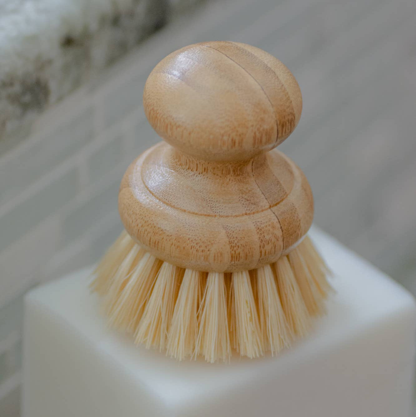 A beige dish washing brush with a bamboo handle and agave fiber bristles.