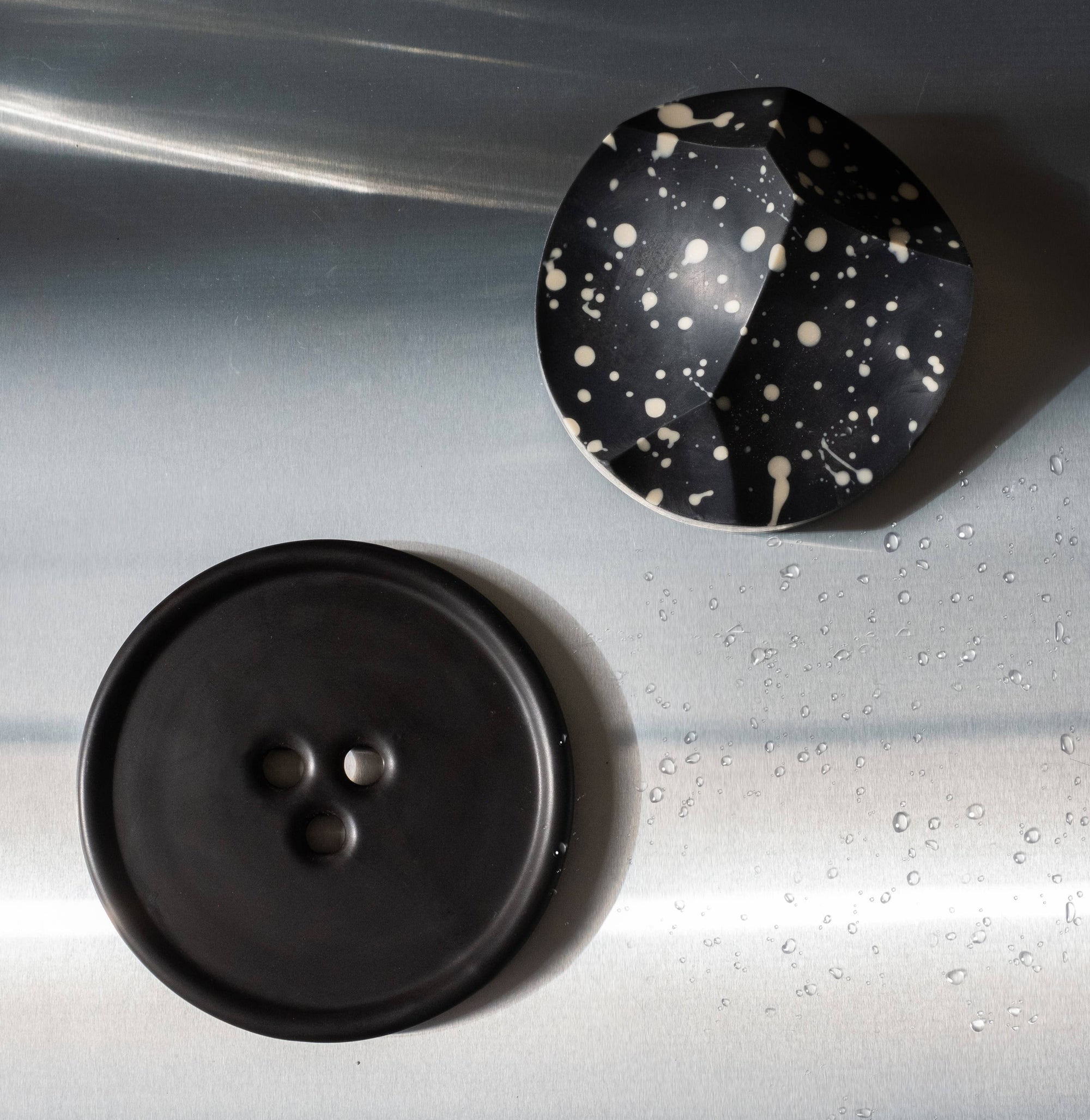 A round black concrete tray with a button-like shape, featuring subtle textures on its surface, designed for holding everyday favorites.