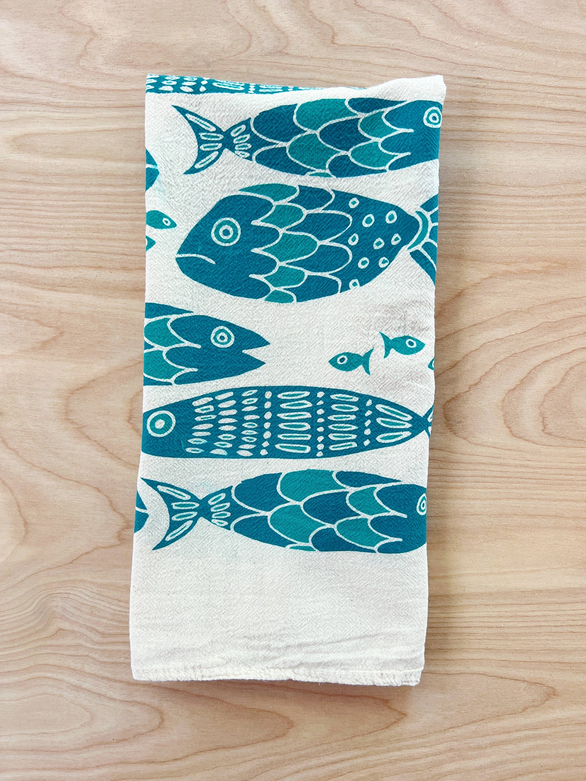 The Noon Designs fish tea towel is white with blue fish printed on it. 