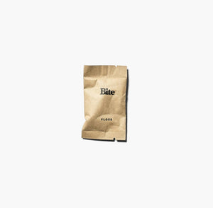 A compostable floss refill packet with the brand name 'Bite' printed on it, placed against a white background.