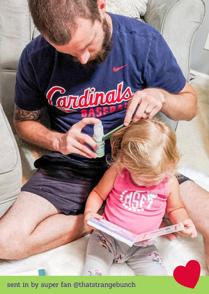 Man applying hair detangler to a child's heir