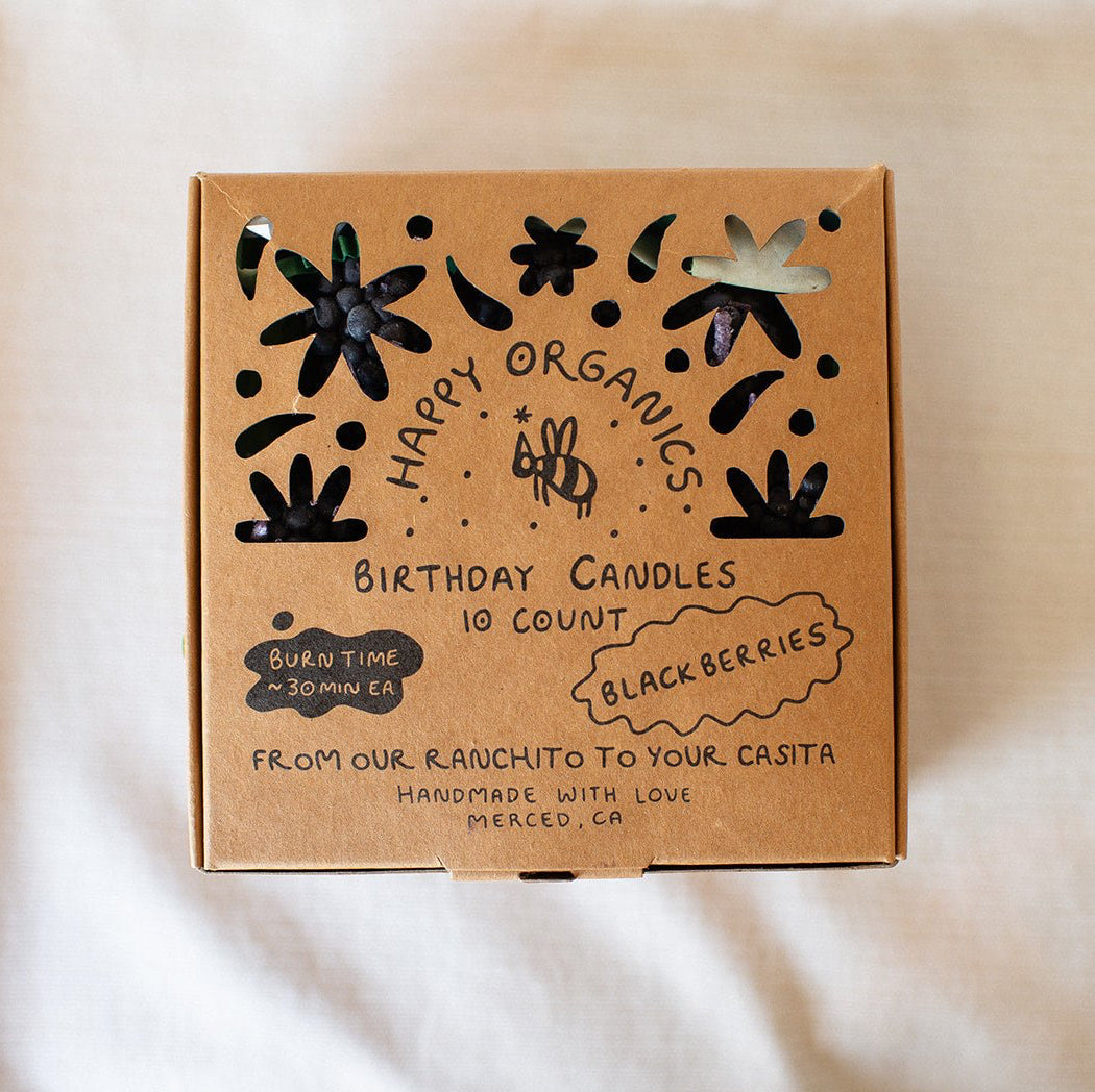 A box of Happy Organics Blackberry Beeswax Birthday Candles in a brown paper box on a light colored background. 
