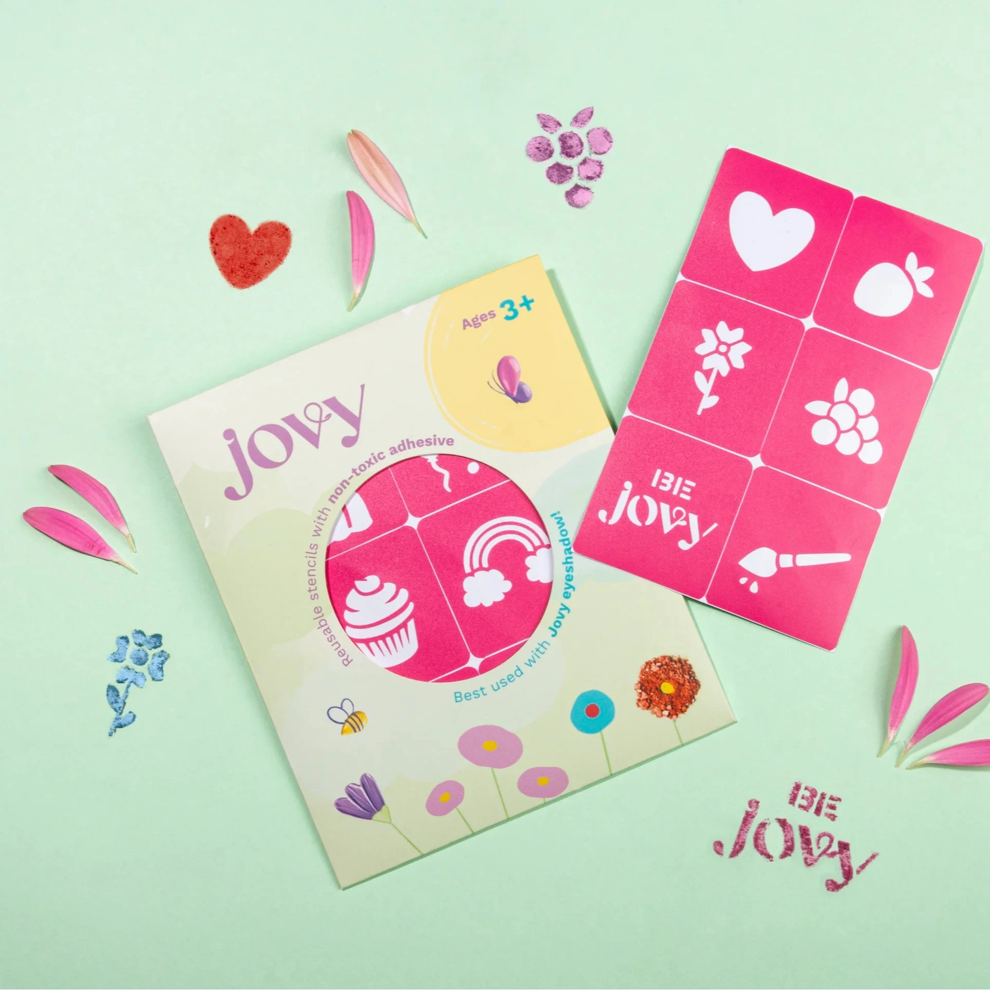 A collection of colorful makeup stencils with designs such as butterflies, flowers, and stars, laid out on a white background, with the brand name 'Jovy' visible on the stencils.