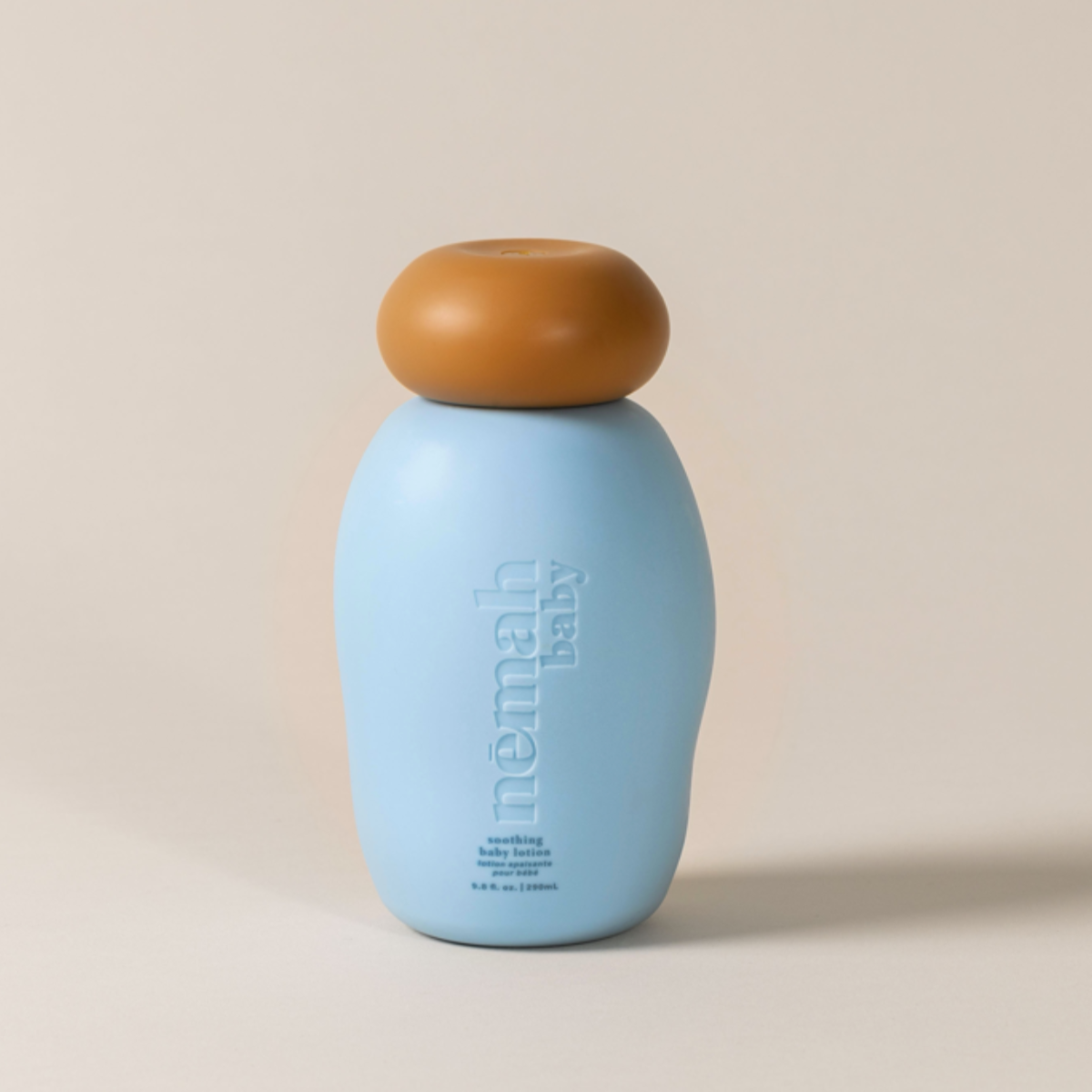 A blue pump bottle labeled 'nämah baby' with a brown cap, set against a neutral background.