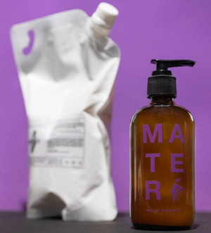 A bottle of mater soap with a refill bag on a purple background. 