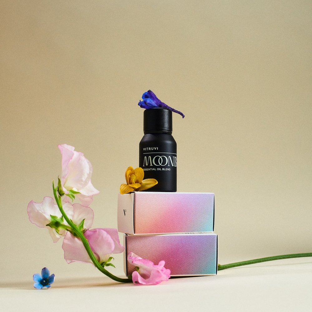 Black bottle labeled 'MOONBEAM' with flowers on a beige background