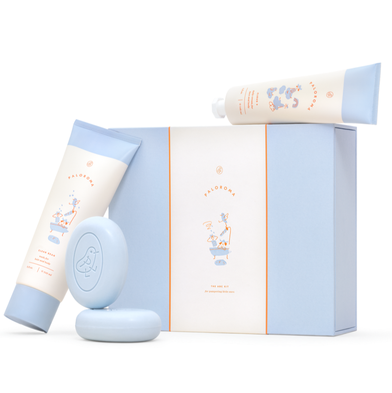 A collection of Paloroma bath time essentials including a wash bottle, a cream bottle, and two cleansing bars, all packaged in a signature Paloroma tissue paper with a bird icon.