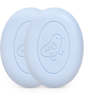 Two light blue oval shaped bars of soap with a baby chick decoration in the mold.