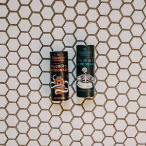 Two tubes of pilgrim's deodorant on a tile floor background. 