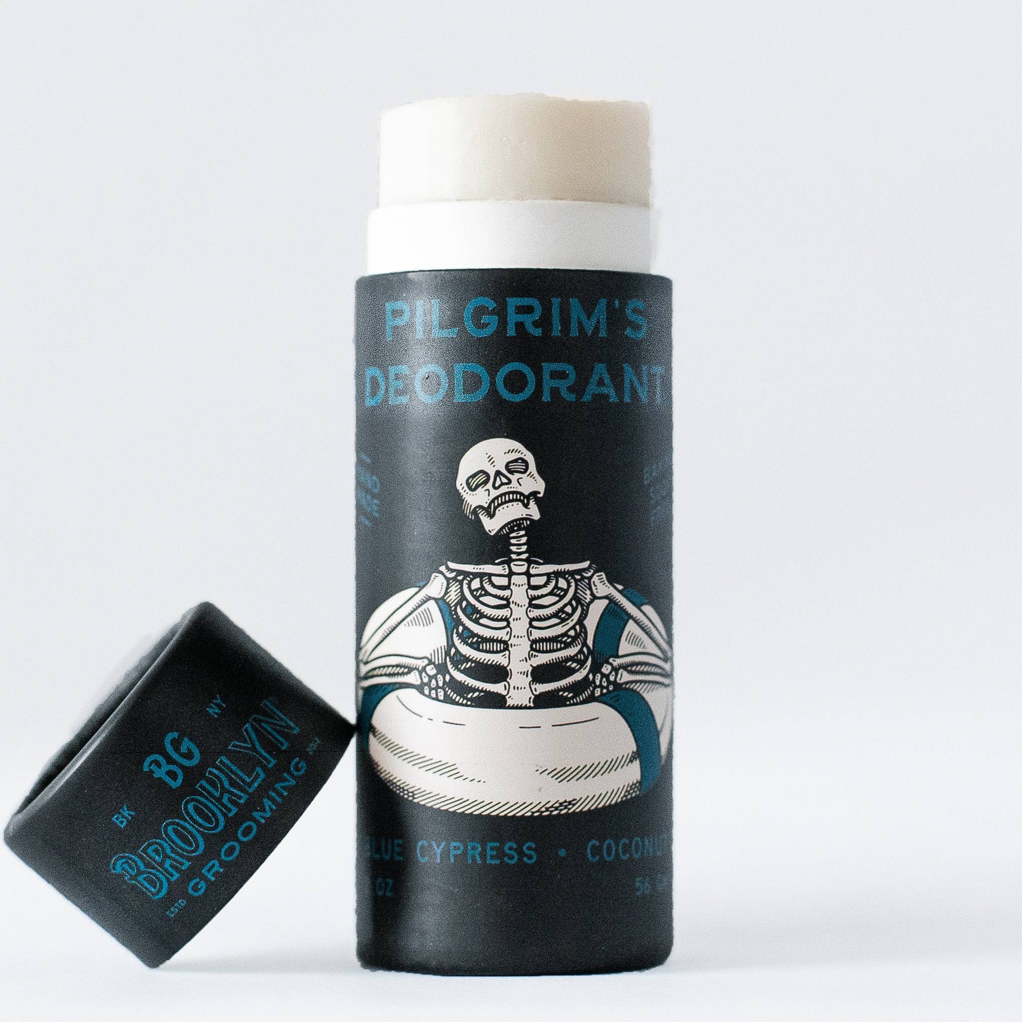 A stick deodorant with a black label featuring a white illustration of a skeleton holding a sign, labeled 'Pilgrim's Deodorant'.