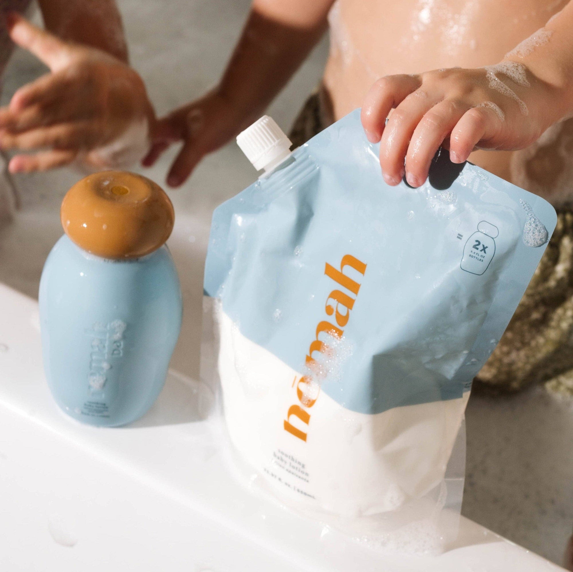 A plastic pouch labeled 'nemah' being held by a child, with another pouch in the background on a bathroom counter.