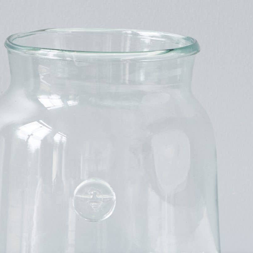 A recycled glass vase with a bee insignia on the side. 