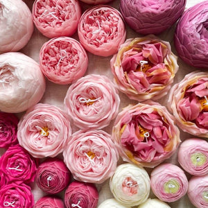 A selection of pink, white, and red candles shaped like roses and peonies. 