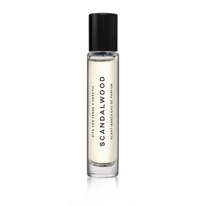 A clear glass bottle with a black cap, labeled 'Scandalwood' by Heretic Parfum.