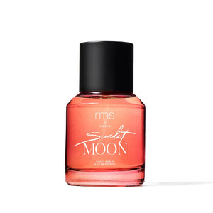 A bottle of RMS Scarlet Moon perfume with a black cap and a pink-reddish liquid inside. The label has 'SCARLET MOON' written in a bold, black font.