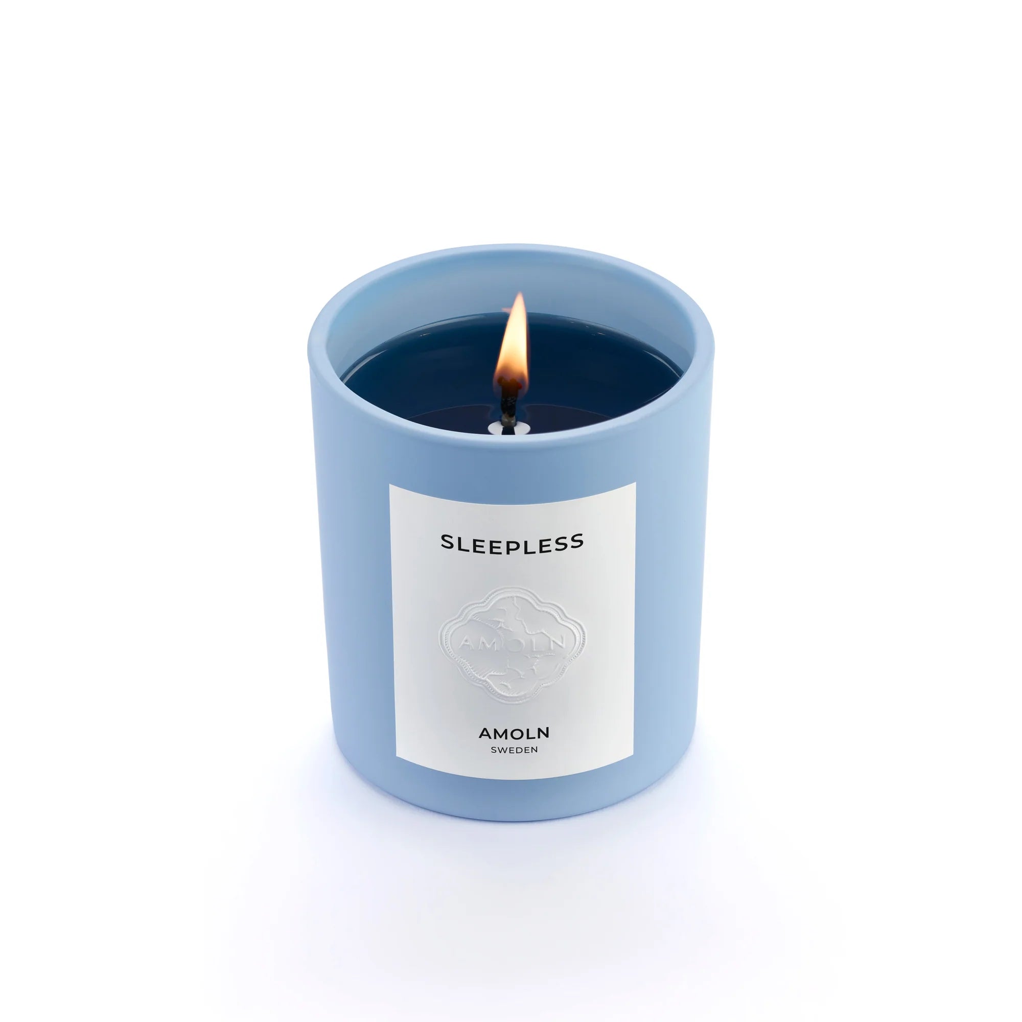 A blue candle with a label reading 'SLEEPLESS AMOLN', indicating the scent and brand.