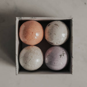 A beige box holding four bath bombs