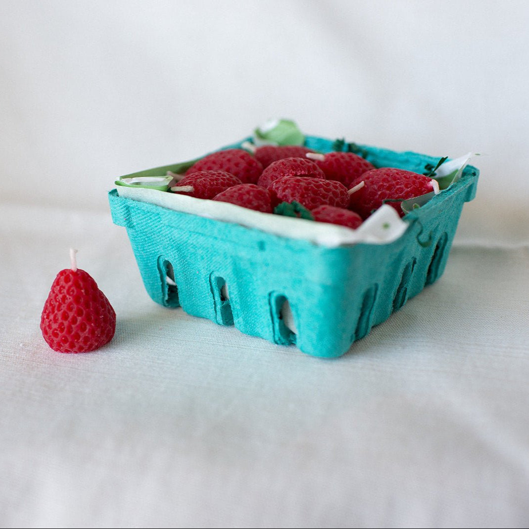 A green produce box full of Happy Organics Strawberry Beeswax Birthday Candles.