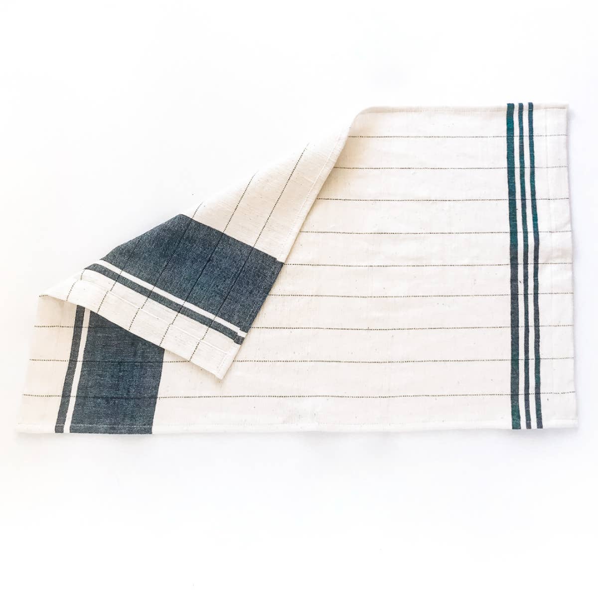 A green and cream colored tea towel on a white background. 
