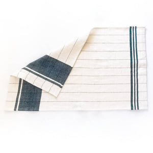 A green and cream colored tea towel on a white background. 