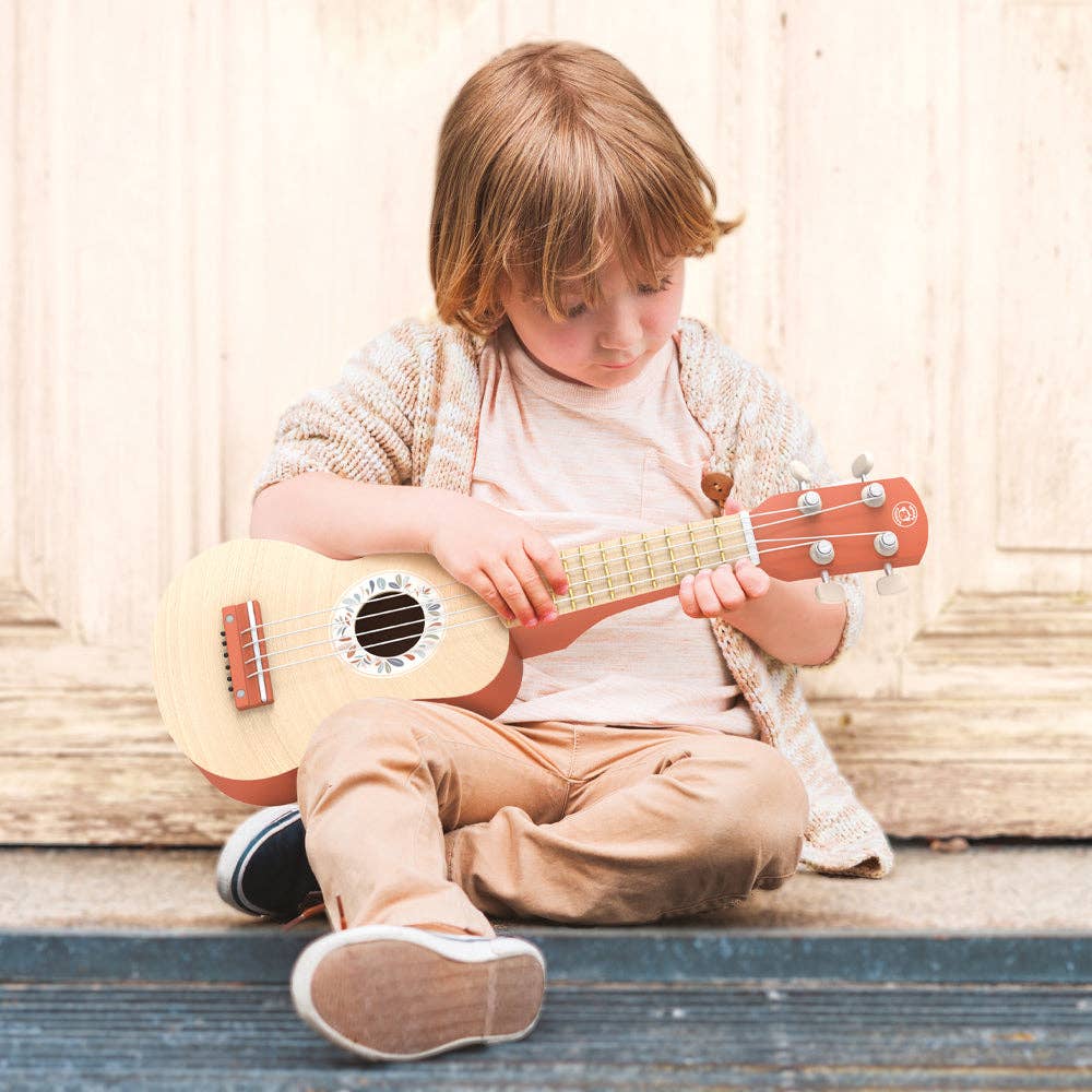 A soft nylon four string toy ukelele in terracotta and wooden color, designed for children with a leaf pattern on the background.