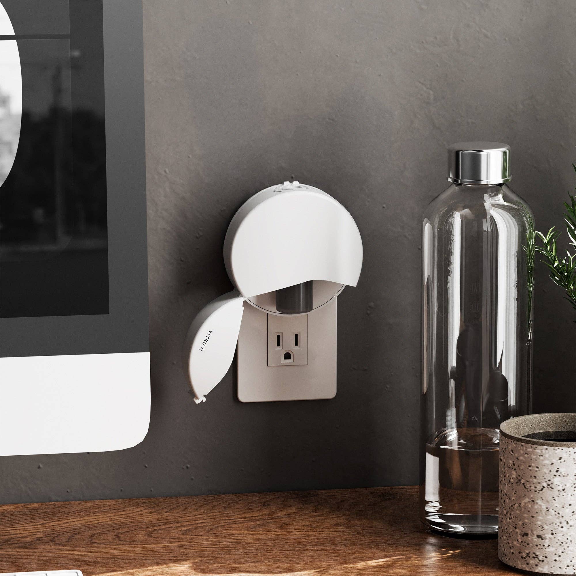 White plug in diffuser attached to a wall outlet with 'Vitruvi' branding on a white background