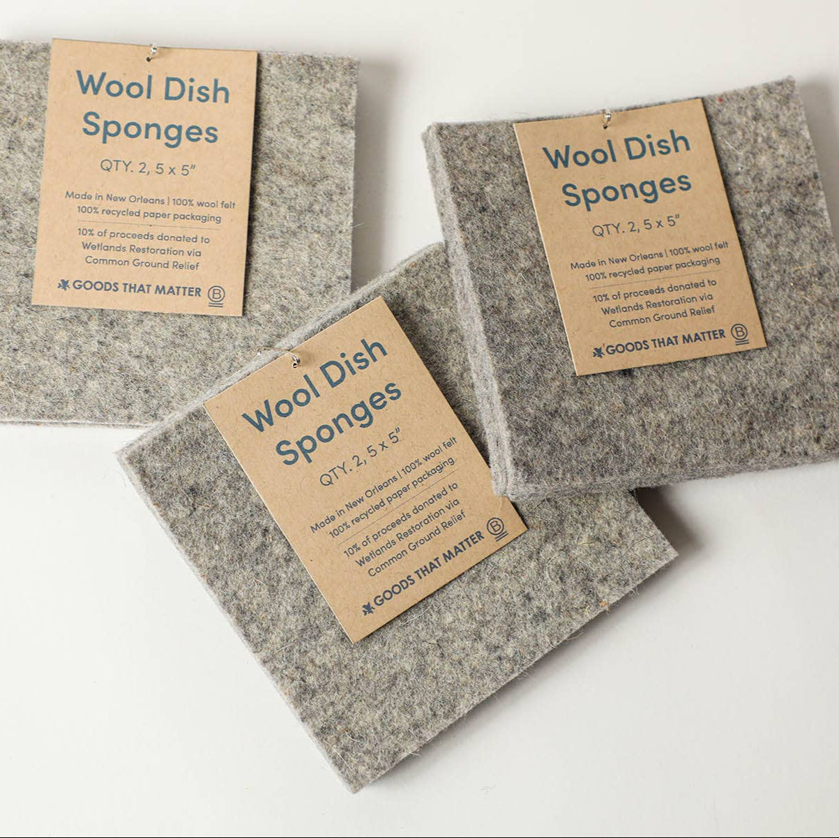 A wool sponge with a brown paper tag, on a light colored surface. 